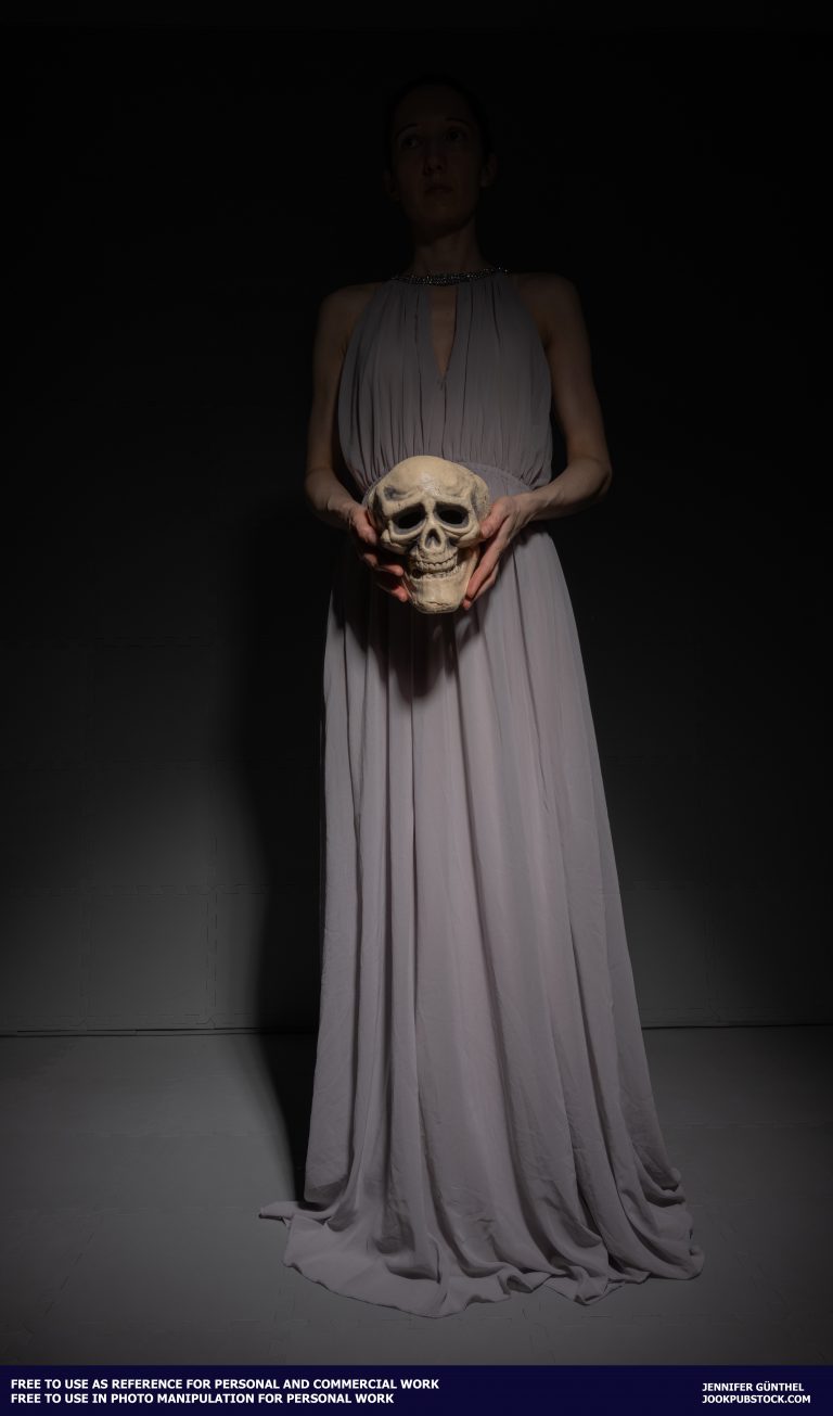 a person in a long dress holding a skull