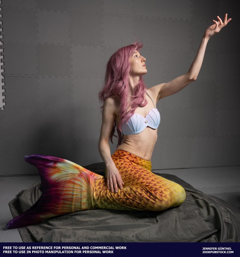 a person wearing a mermaid costume and sitting on a stone