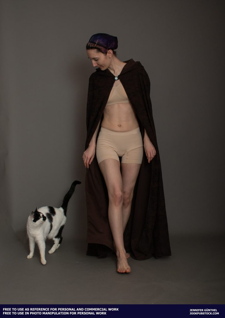a person wearing a cloak and looking at a cat
